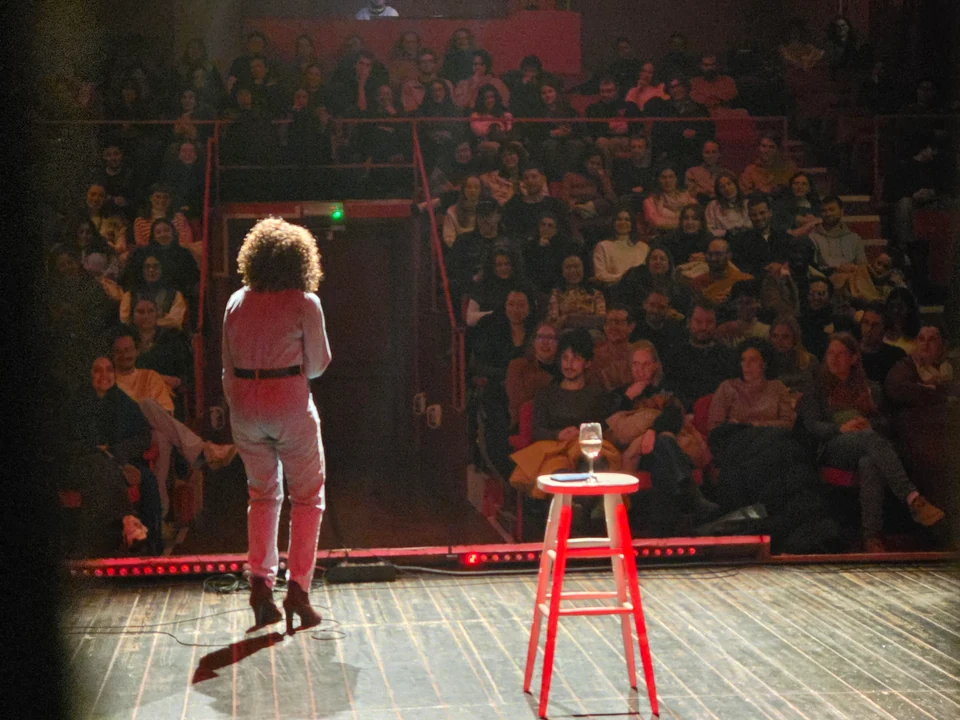 Comedian on stage facing a packed Tinnenpot audience