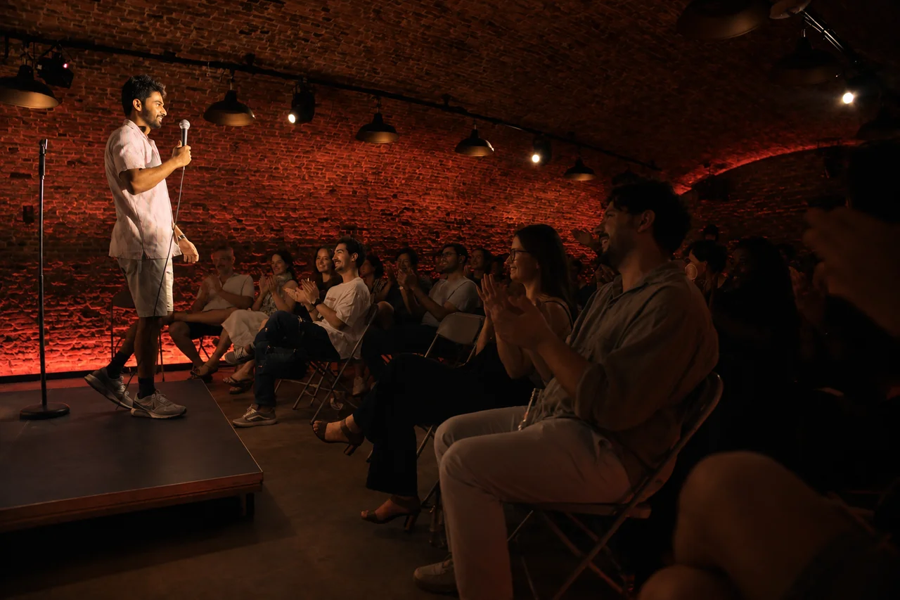 A comedian performing beside the seated audience beneath Vertigo’s brick arches in Antwerp.